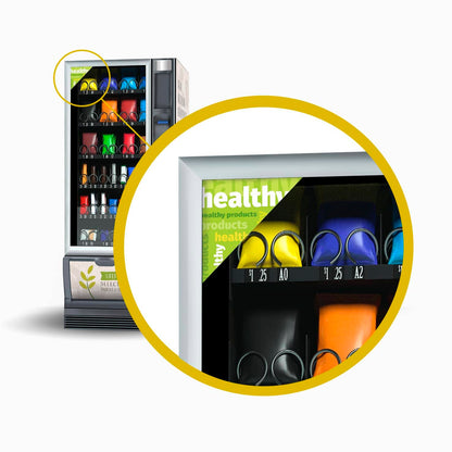 Bannière publicitaire triangulaire verte pour produits sains, installée sur la vitre d’un distributeur automatique de snacks